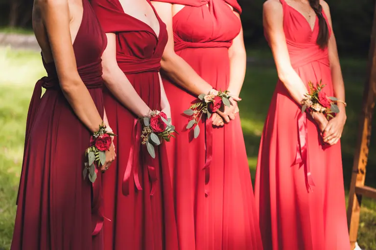 A row of bridesmaids wearing rose wrist corsages.