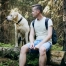 Man sitting on a log with his dog in the forest.