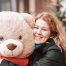 Woman hugging a giant teddy bear that's wearing a bandana.
