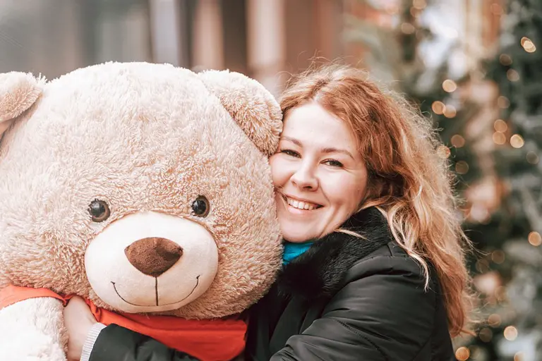 Woman hugging a giant teddy bear that's wearing a bandana.