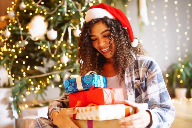 Young woman with a lap full of Christmas presents.